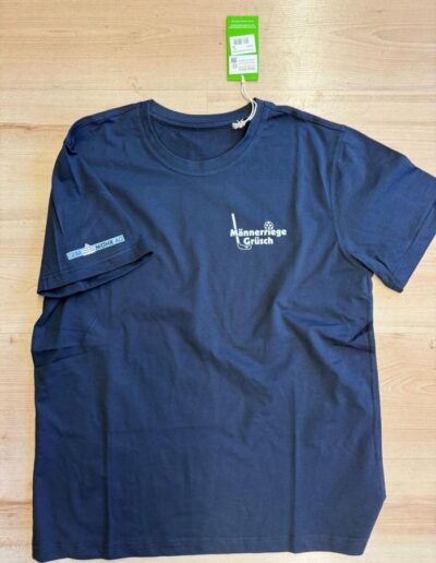 Dunkelblaues T-Shirt mit weissem Textildruck auf Brust und Ärmel, grünes Preisschild am Kragen, flach liegend.